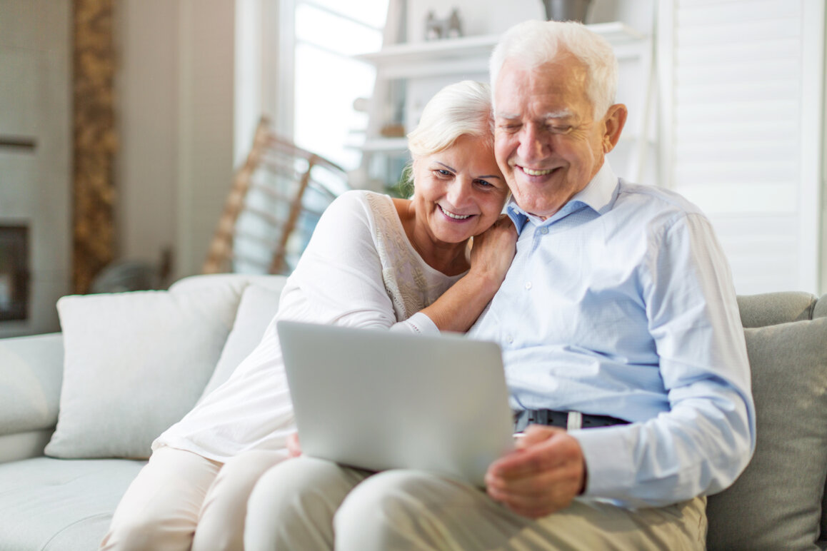 Senior couple using laptop computer at home to review their dental treatment plan.