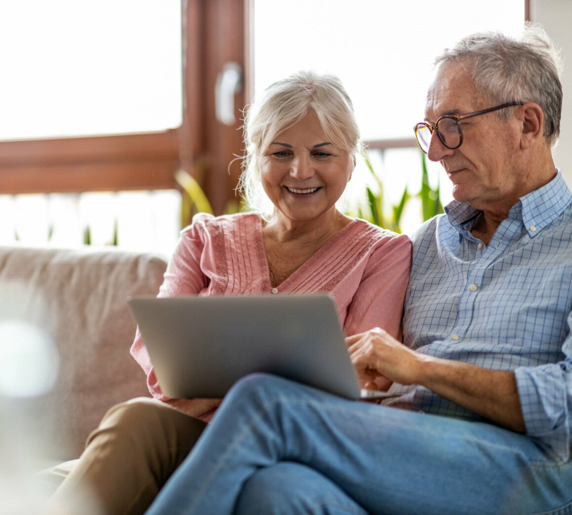 Mature couple, preparing for their dentistry at home visit, using a laptop to submit their registrations.